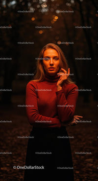 Thoughtful woman standing in warm autumn forest light