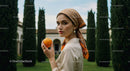 Stylish Woman Holding an Orange in a Bright Outdoor Setting