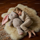 Child cuddling giant plush bunny on soft rug