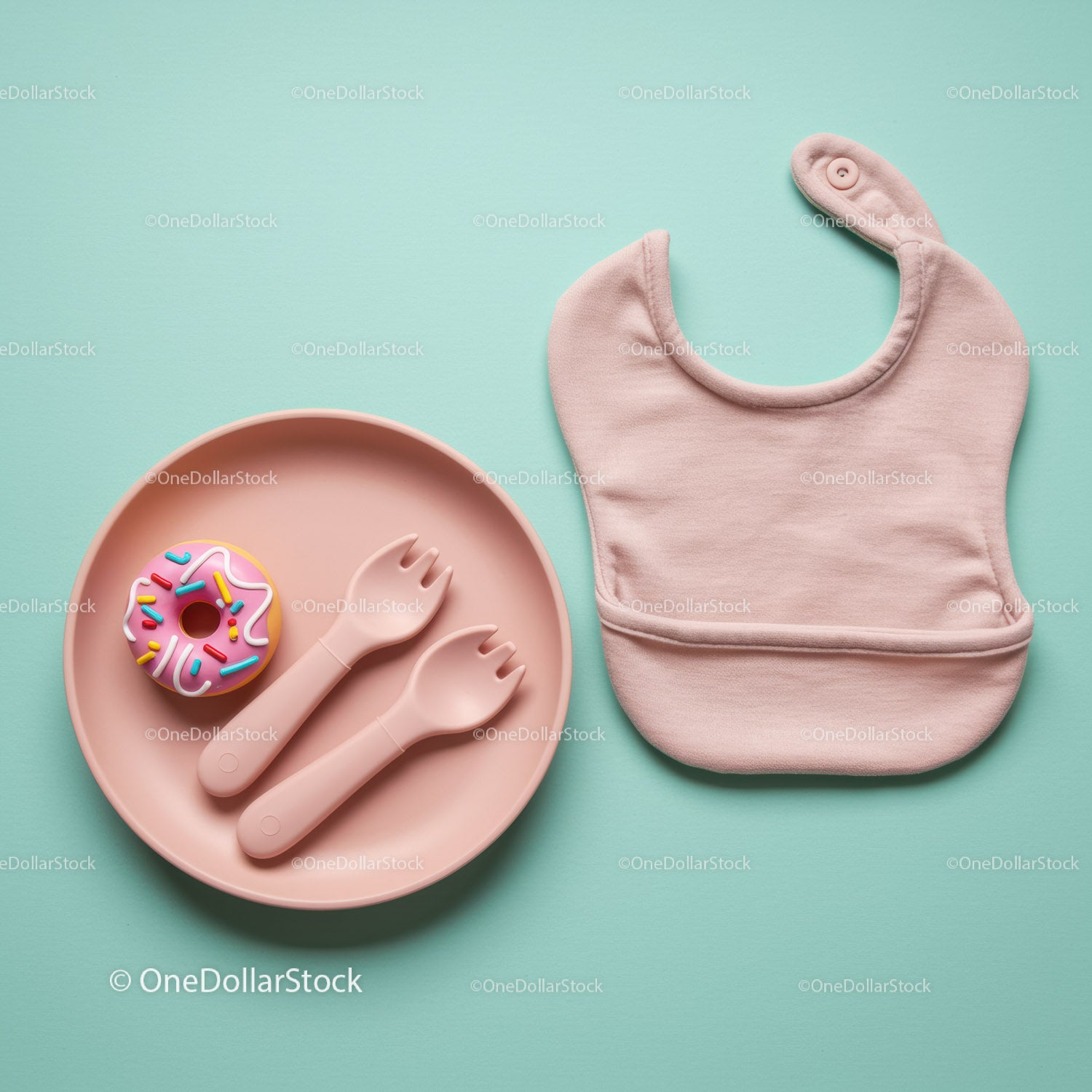 Baby feeding set with bib and toy donut on pastel background