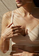 Elegant Woman Applying Body Oil with Sunlit Skin and Beige Top