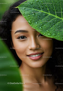 Beautiful Woman Peeking Through Green Tropical Leaves with Water Droplets