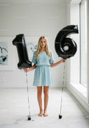 Teenage girl holding black balloons shaped as number sixteen