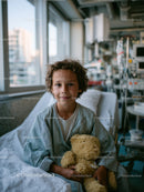 Child in Hospital Holding Teddy Bear in Medical Ward