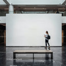 Woman walking past blank gallery wall in modern museum