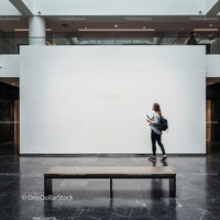 Woman walking past blank gallery wall in modern museum