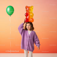 Little girl in purple sweater holding giant gummy bear