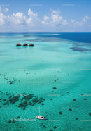Tropical Overwater Bungalows and Sailing Boat in Clear Blue Sea