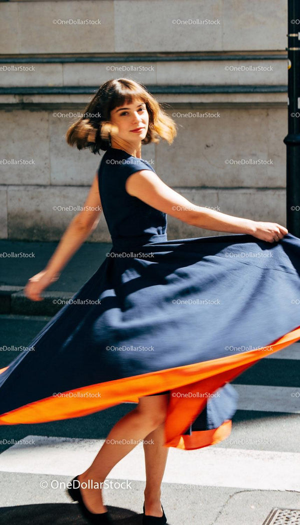 Woman Twirling in Elegant Navy Dress with Orange Accent