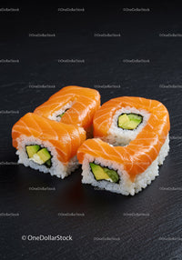 Fresh salmon sushi rolls with avocado on black slate
