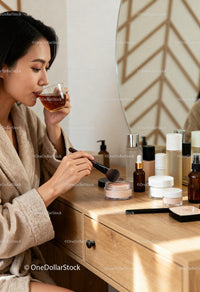 Woman enjoying tea while applying makeup at vanity