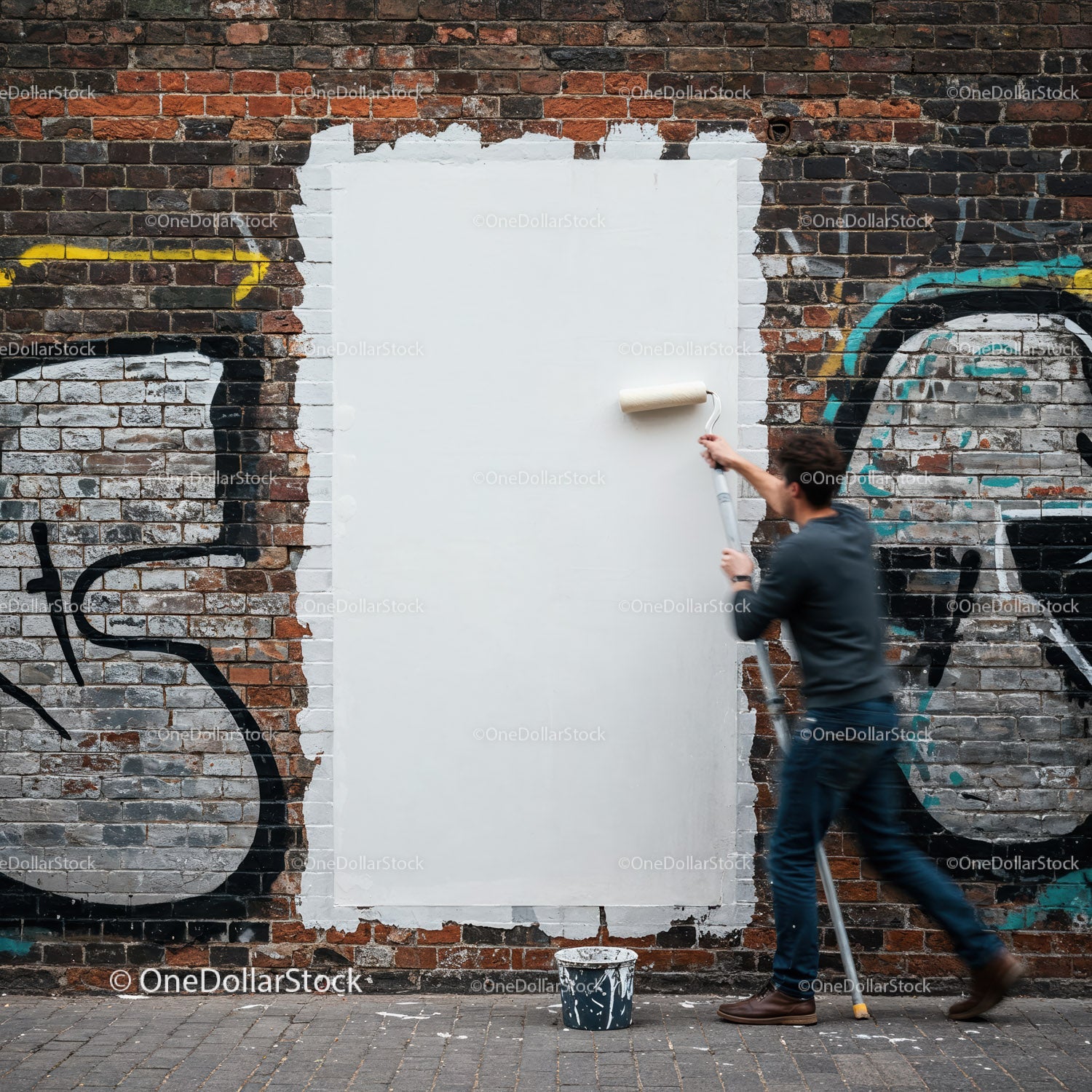 Mężczyzna malujący graffiti białym wałkiem na ceglanej ścianie