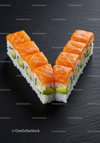 Fresh salmon sushi rolls arranged in a V shape on slate