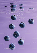 Fresh blueberries floating underwater in purple liquid