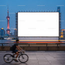 Cyclist passing a large blank billboard by the riverside
