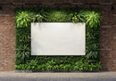 Blank whiteboard surrounded by lush green plants on brick wall