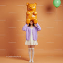 Young woman holding giant gummy bear headpiece indoors