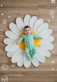 Smiling baby lying on large daisy flower decor