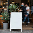 Blank white sidewalk sign outside busy cafe entrance
