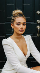 Confident woman in elegant white dress sitting by door