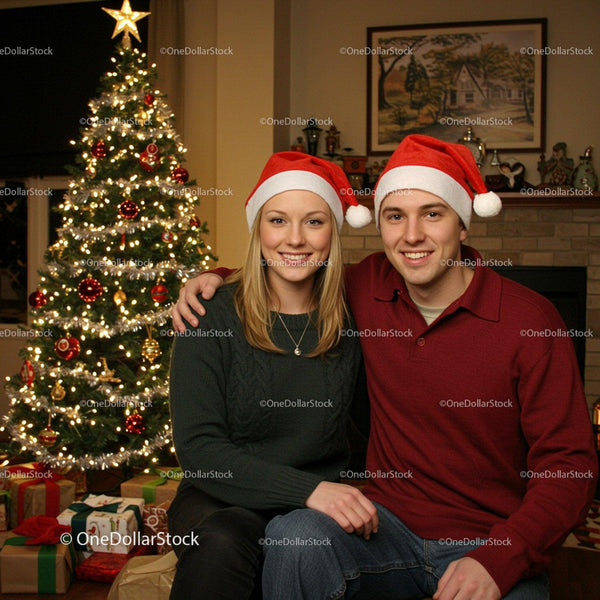 Smiling couple in Santa hats by decorated Christmas tree
