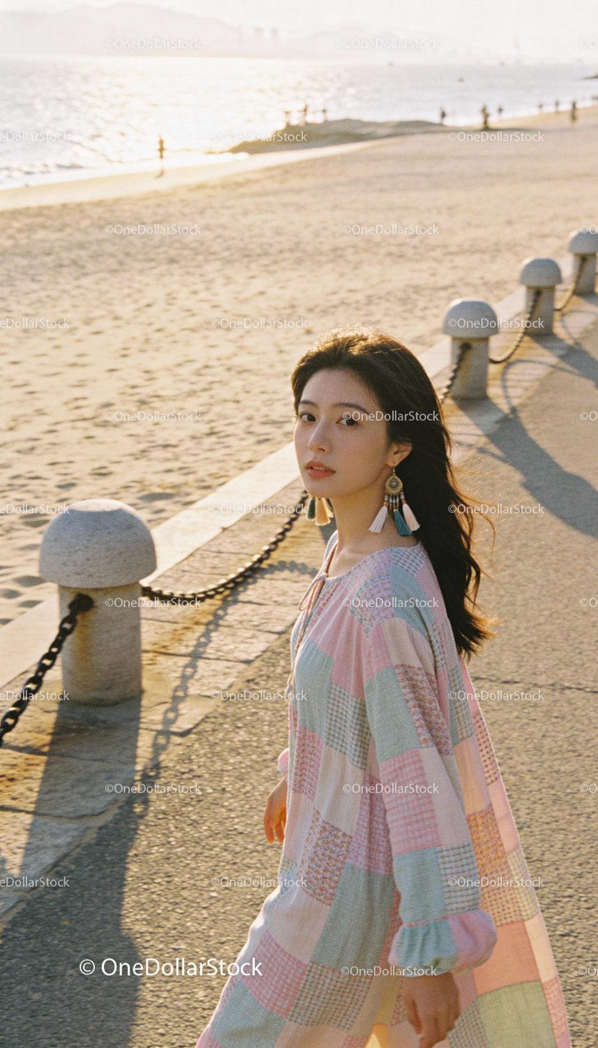 Young woman in pastel dress enjoying a sunny beach walk