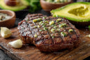Juicy Grilled Beef Steak with Garlic and Avocado on Wooden Board