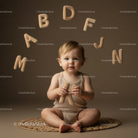 Toddler exploring plush alphabet letters while sitting crosslegged
