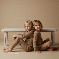 Two children sitting back to back on beige background