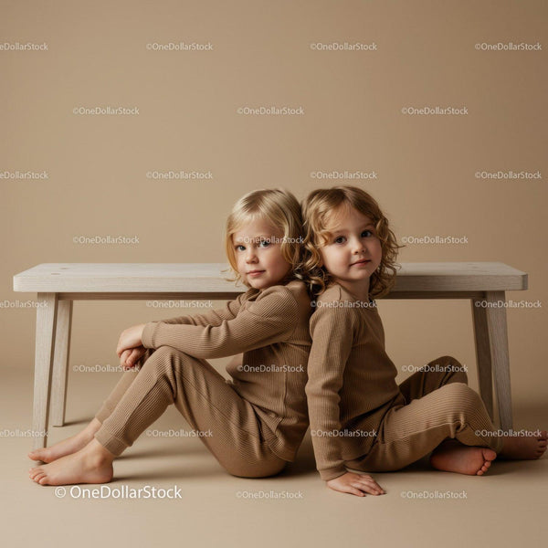 Two children sitting back to back on beige background