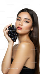 Young Woman with Long Brunette Hair Holding Black Grapes in Studio