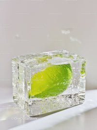 Fresh lime frozen inside clear ice cube on white surface