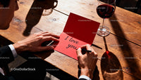 Man Writing Love Message on Red Card with Wine Glass