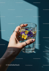Hand Holding Glass of Water with Floating Pansy Flowers