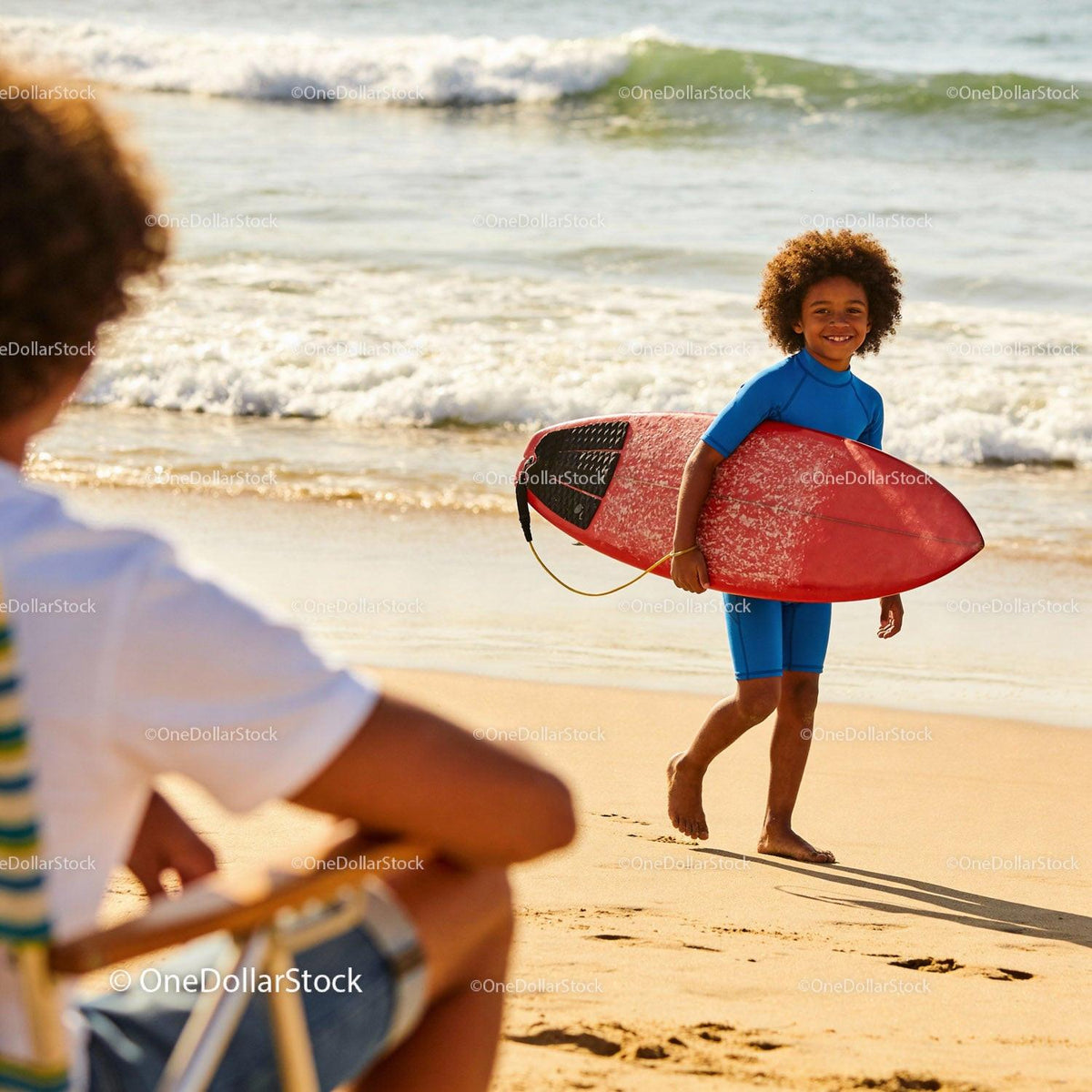 Smiling boy walking on beach with red surfboard