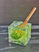 Glass Cube Filled With Green Matcha Ice and Whisk