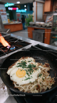 Fried Egg with Noodles in Cast Iron Skillet in Commercial Kitchen
