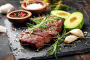 Fresh Raw Beef Steak with Avocado and Herbs on Dark Slate Plate