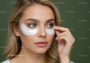Close-up of a woman with under-eye patches applying skincare treatment
