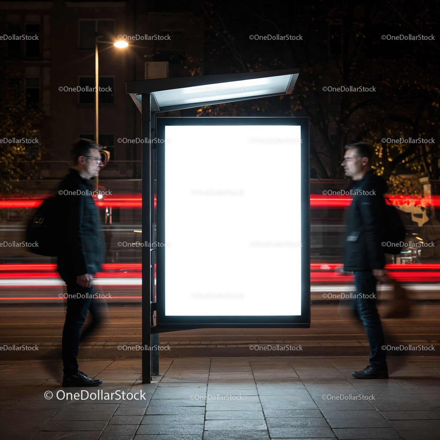 Blurred men passing illuminated city bus stop poster at night
