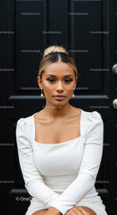 Elegant woman in white dress sitting against black door