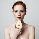 Elegant Red-Haired Woman Holding Fresh Pear in Minimalist Portrait