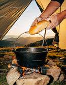 Hands Placing Fresh Bread over Campfire Pot at Sunset
