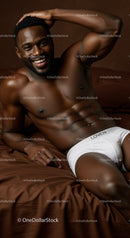 Smiling athletic man reclining on bed in white underwear
