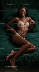 Smiling woman relaxing on dark green bed in beige lingerie