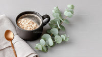 Black Coffee Mug with Oatmeal and Green Eucalyptus on Light Background