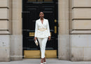 Elegant woman in white suit standing by black door
