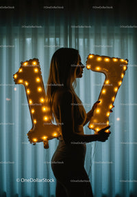 Silhouette of Woman Holding Lighted Number Balloons 17