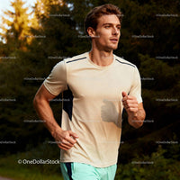 Focused young man running through sunlit forest trail