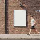 Runner passing empty urban billboard on brick wall